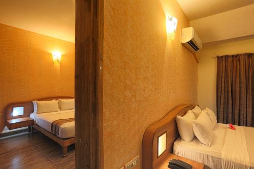 a hotel room with two beds and a mirror at Calangute Residency in Calangute