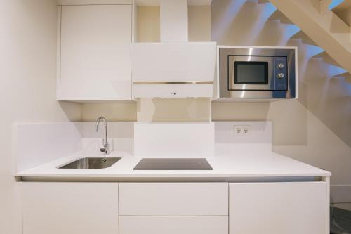 a white kitchen with a sink and a microwave at Debambú Atarazanas in Málaga