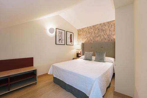 a bedroom with a white bed and a tv at Debambú Atarazanas in Málaga