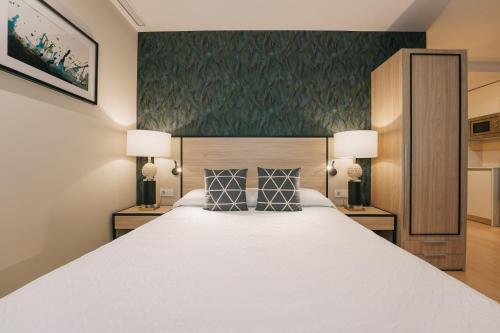 a bedroom with a large white bed with two lamps at Debambú Atarazanas in Málaga