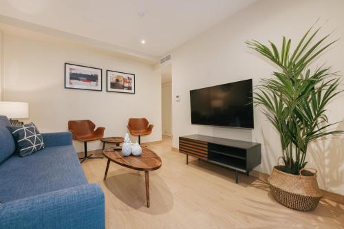 a living room with a blue couch and a tv at Debambú Atarazanas in Málaga