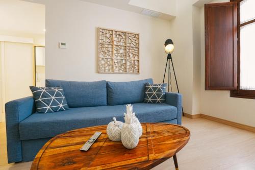 a living room with a blue couch and a table at Debambú Atarazanas in Málaga