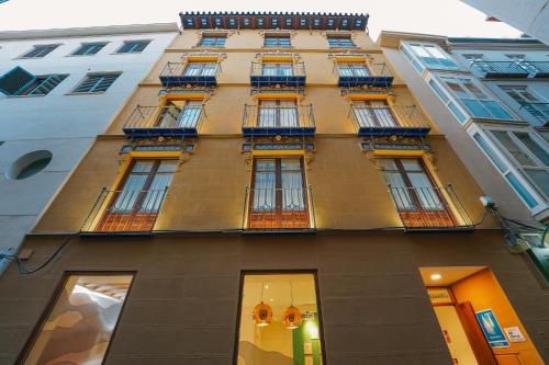 un edificio alto con balcones a un lado. en Debambú Atarazanas, en Málaga