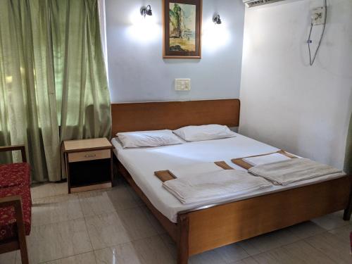 niewielka sypialnia z łóżkiem z białą pościelą w obiekcie Farmagudi Residency w mieście Ponda