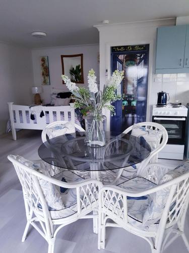 una mesa de cristal con sillas blancas y un jarrón de flores en Black Sheep Cottage Hay en Hay