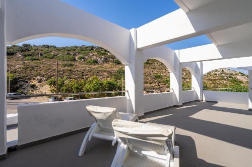 a balcony with two chairs and a view of a hill at Ladiko Suites - Faliraki in Faliraki