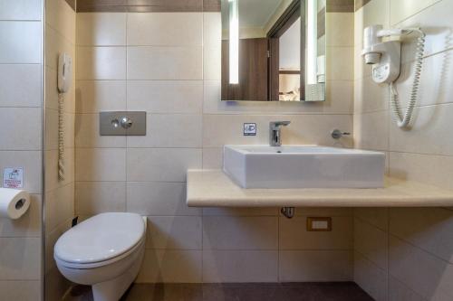 a bathroom with a sink and a toilet and a phone at Ladiko Suites - Faliraki in Faliraki