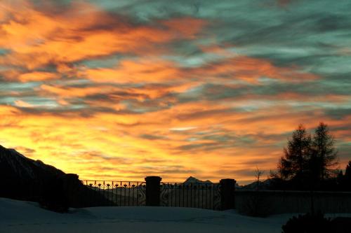 a sunset with a fence in the snow at Hotel Lärchenhof Natur in Seefeld in Tirol