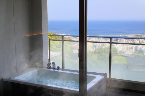a bath tub in front of a large window at Atami Fuga in Atami