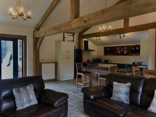 a living room with leather couches and a kitchen at Trelaske Mill Cider Barn-with Hot Tub, Fire Pit BBQ in Lewannick
