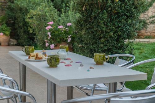 a white table with two cups and a plate of food on it at Arsinoi Studios and Apartments in Kalamaki Heraklion