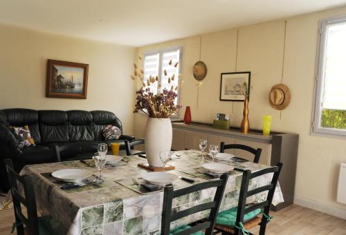 une table de salle à manger avec un vase de fleurs dessus dans l'établissement Maison de vacances 3 chambres à 400 m de la plage Kairon - Saint Pair sur mer, à Saint-Pair-sur-Mer