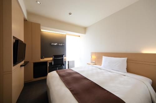 a hotel room with a bed and a television at Hakata Tokyu REI Hotel in Fukuoka