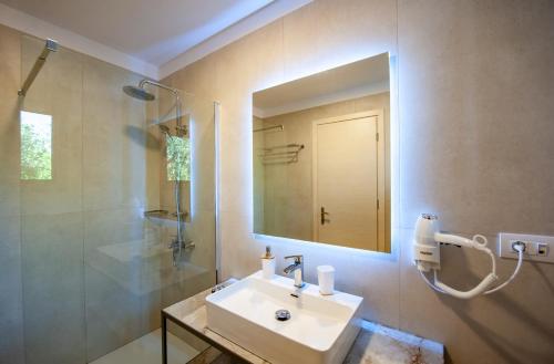 bagno con lavandino, doccia e specchio di Alonaki Resort a Preveza