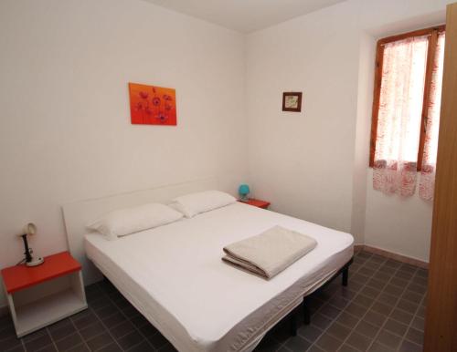 Cama blanca en habitación con mesa roja en Villa Manu appartamento 02, en Rosolina Mare