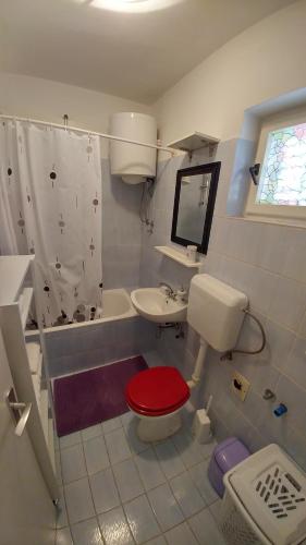 a bathroom with a toilet and a sink and a tub at Apartment Eneja in Rab