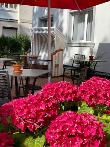 a bunch of pink flowers on a patio with an umbrella at Hotel Altes Kurhaus in Baabe