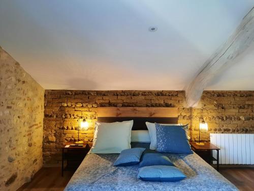 a bedroom with a large bed with blue pillows at Les Chambres de Lili in Saint-Loup