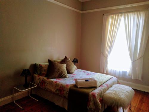 a small bedroom with a bed with a window at Cozy Cottage Van Reenen in Van Reenen