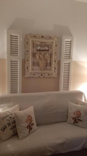 a white couch with pillows and a heart picture on the wall at Nel Giardino di Carla in Rapallo