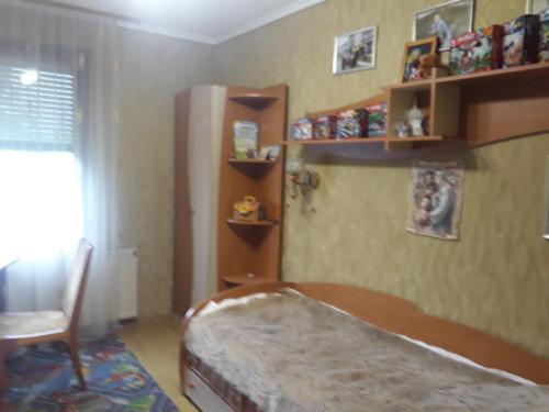 a bedroom with a bed and a chair and shelves at гостинна ВАША ХАТА in Volovets