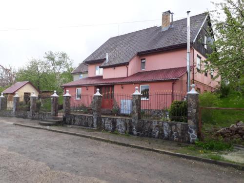 a pink house with a fence in front of it at гостинна ВАША ХАТА in Volovets