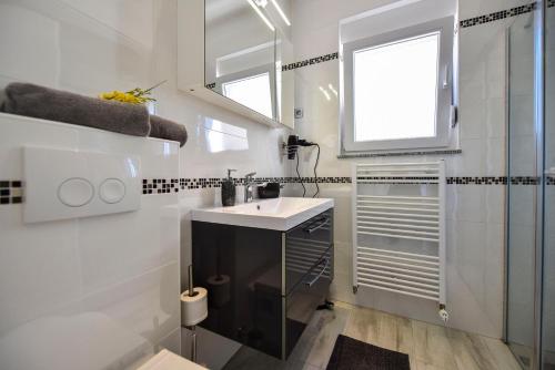 La salle de bains blanche est pourvue d'un lavabo et d'une douche. dans l'établissement Moderner Bungalow mit Meerblick, à Lun