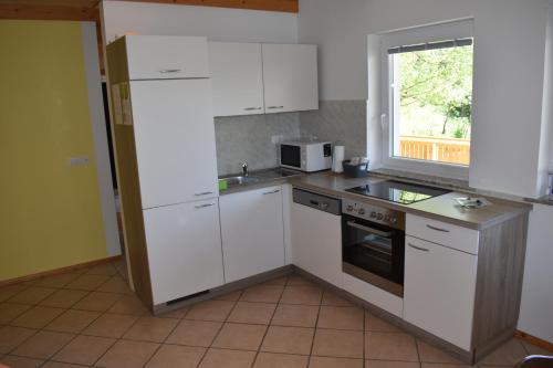 a kitchen with white cabinets and a window at Apartment Murka in Begunje na Gorenjskem