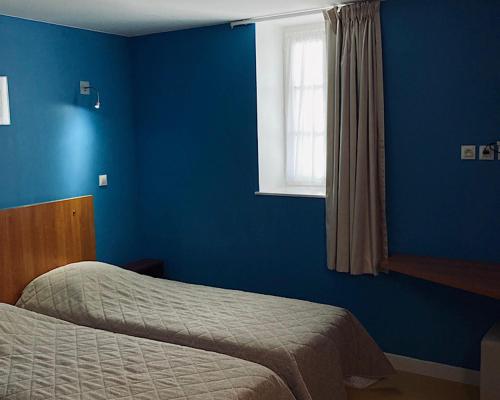 a blue bedroom with a bed and a window at L'ETAPE DE SANTENAY in Santenay