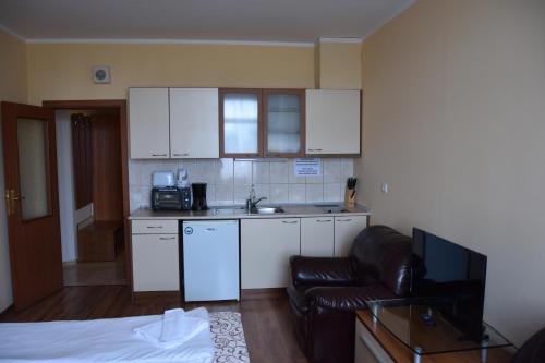 a small kitchen with white cabinets and a couch at Persey Flora Apartments in Borovets