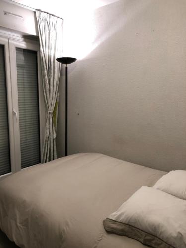 a bed in a bedroom with a window and a lamp at LE CLOS du LAC STUDIO TERRASSE JARDIN et cave Vélos fermée RDC in Annecy