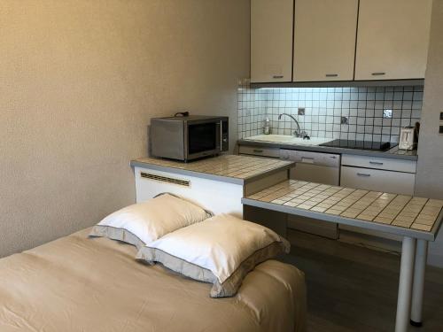 une petite cuisine avec un micro-ondes et une table avec des oreillers dans l'établissement LE CLOS du LAC STUDIO TERRASSE JARDIN et cave Vélos fermée RDC, à Annecy