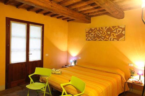 una camera con un letto e due sedie verdi di Appartamento Il Leccio Pian delle more a Sassetta