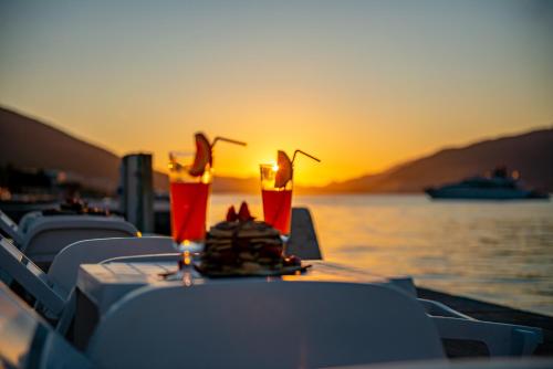 a table with chairs and drinks on a boat with the sunset at Apartments Dragojević in Tivat