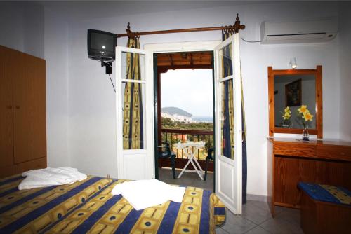 1 dormitorio con 1 cama y puerta corredera de cristal en Alexandros Rooms & Studios, en Skopelos Town