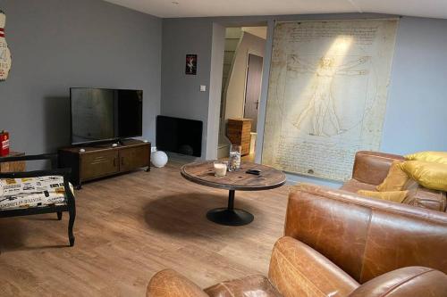 un salon avec un canapé, une table et une télévision dans l'établissement Maison de pêcheur à 10 minutes de la plage à pieds, à Cayeux-sur-Mer