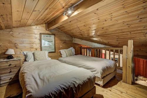 une chambre avec deux lits dans une cabane en rondins dans l'établissement MGM Parc Couttet, à Chamonix-Mont-Blanc