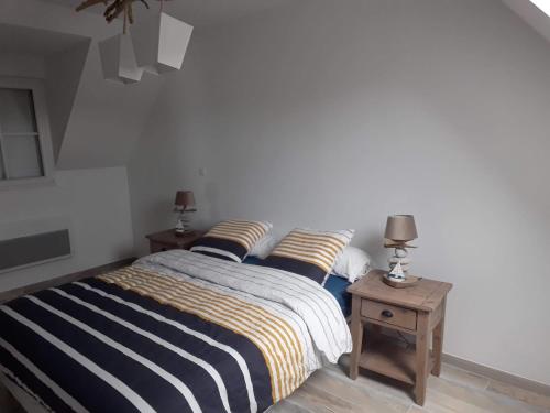 a bedroom with a bed with striped sheets and two tables at Le Chant des Vagues in Audinghen