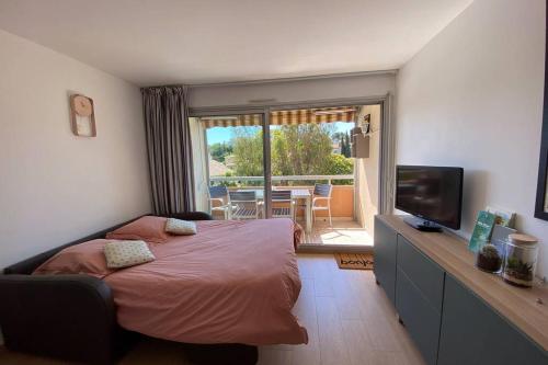 une chambre avec un lit et une télévision et un balcon dans l'établissement St-Raphaël - joli T1 au port de Santa-Lucia, à Saint-Raphaël