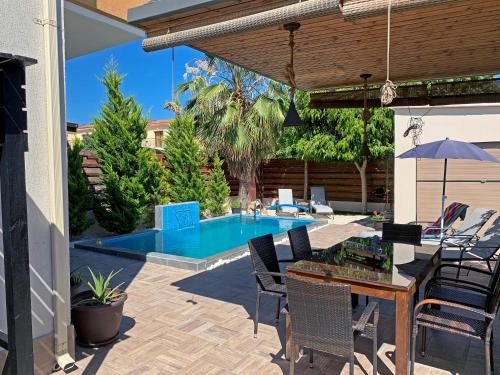 un patio con mesa y sillas y una piscina en Shanti Paphos Villa en Pafos