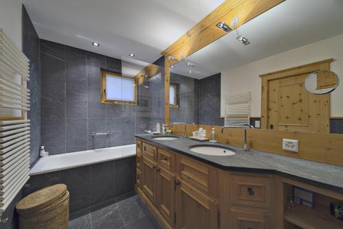 ein Badezimmer mit einem Waschbecken, einer Badewanne und einem Spiegel in der Unterkunft Sur Puoz 13 - Samedan in Samedan