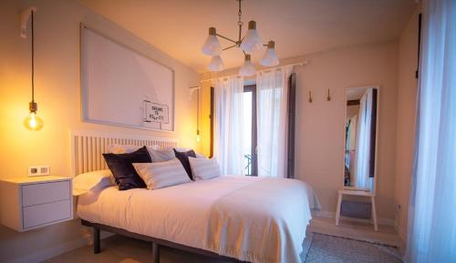 ein Schlafzimmer mit einem weißen Bett und einem Fenster in der Unterkunft Apartamentos UXAMA LUXURY EPONA - junto a la Plaza Mayor in El Burgo de Osma-Ciudad de Osma