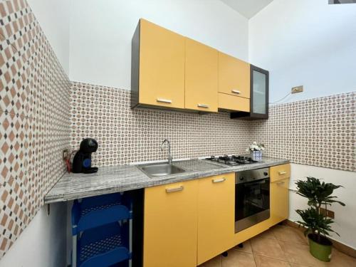 kuchnia z żółtymi szafkami i zlewem w obiekcie Apartment in the center w mieście Terrasini