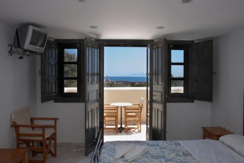 a bedroom with a bed and a balcony with a table at Dagris Villa Studios in Kamari