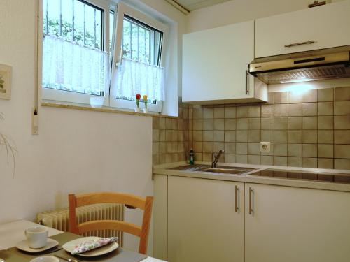 a kitchen with white cabinets and a sink and a table at Ferien-Oase Bad Dürrheim in Bad Dürrheim