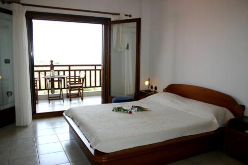 a bedroom with a bed with a view of a balcony at Studios Erotokritos in Ammouliani