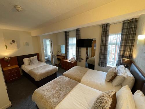 a hotel room with two beds and a television at Ruskin Hotel in Blackpool