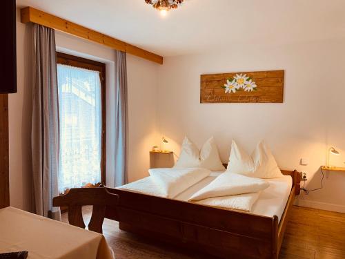 1 dormitorio con 1 cama con sábanas blancas y ventana en Pension Jagerhof - Sommercard Inkl - 5 Min zum Hochzeiger, en Jerzens