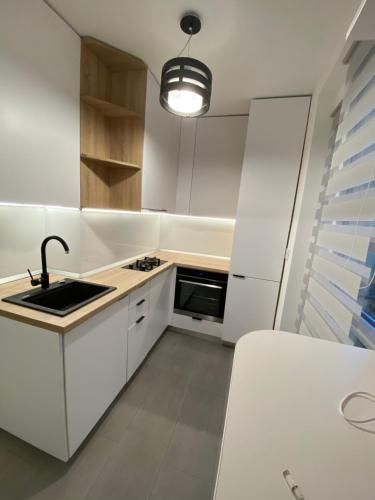 una pequeña cocina con armarios blancos y fregadero en Cozy apartment in the Business area of Bucharest, en Bucarest