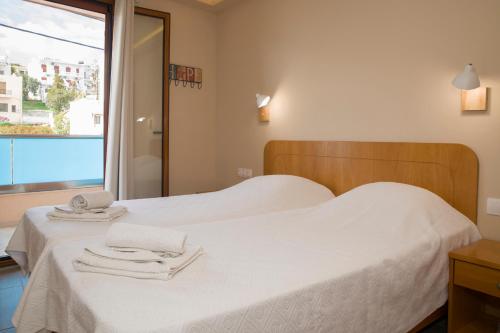 a bedroom with a white bed with towels on it at Minos Boutique Hotel in Agia Galini